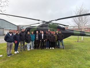 A group of students standing in front of a black helicopter